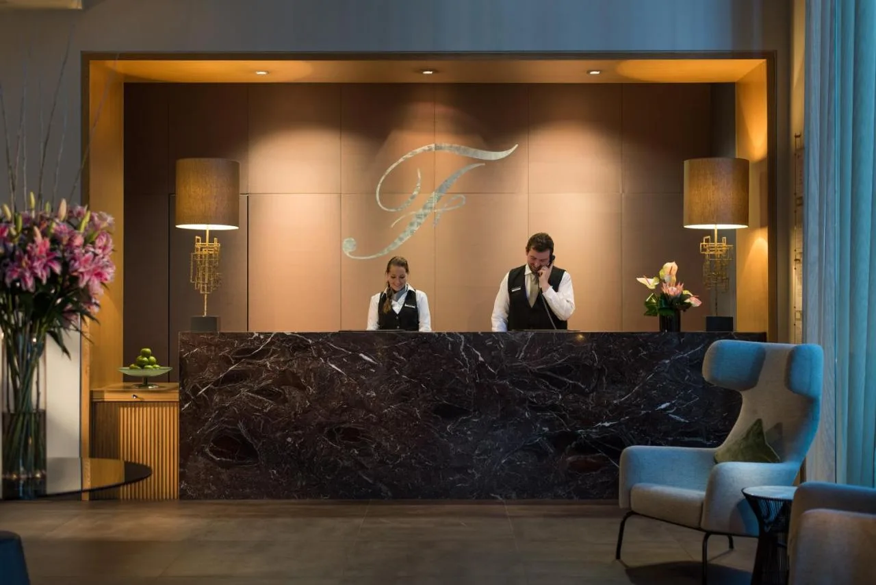 two men standing behind a counter in a hotel lobby at The Fitzwilliam Hotel Belfast in Belfast