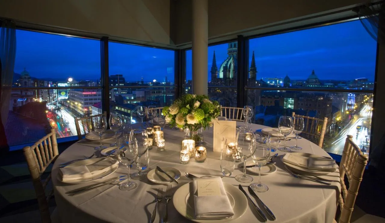 a dining table with a view of a city at The Fitzwilliam Hotel Belfast in Belfast