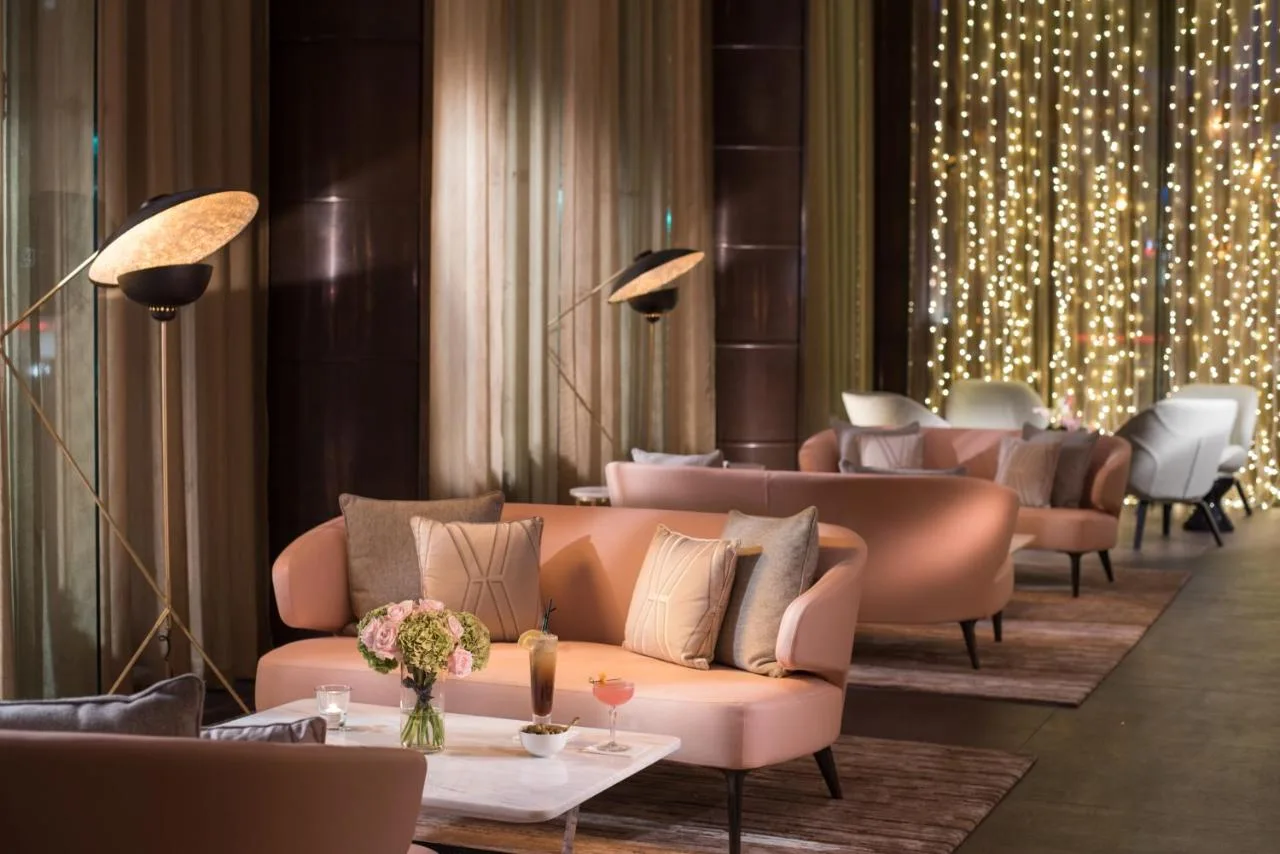 a lobby with pink couches and tables and lights at The Fitzwilliam Hotel Belfast in Belfast