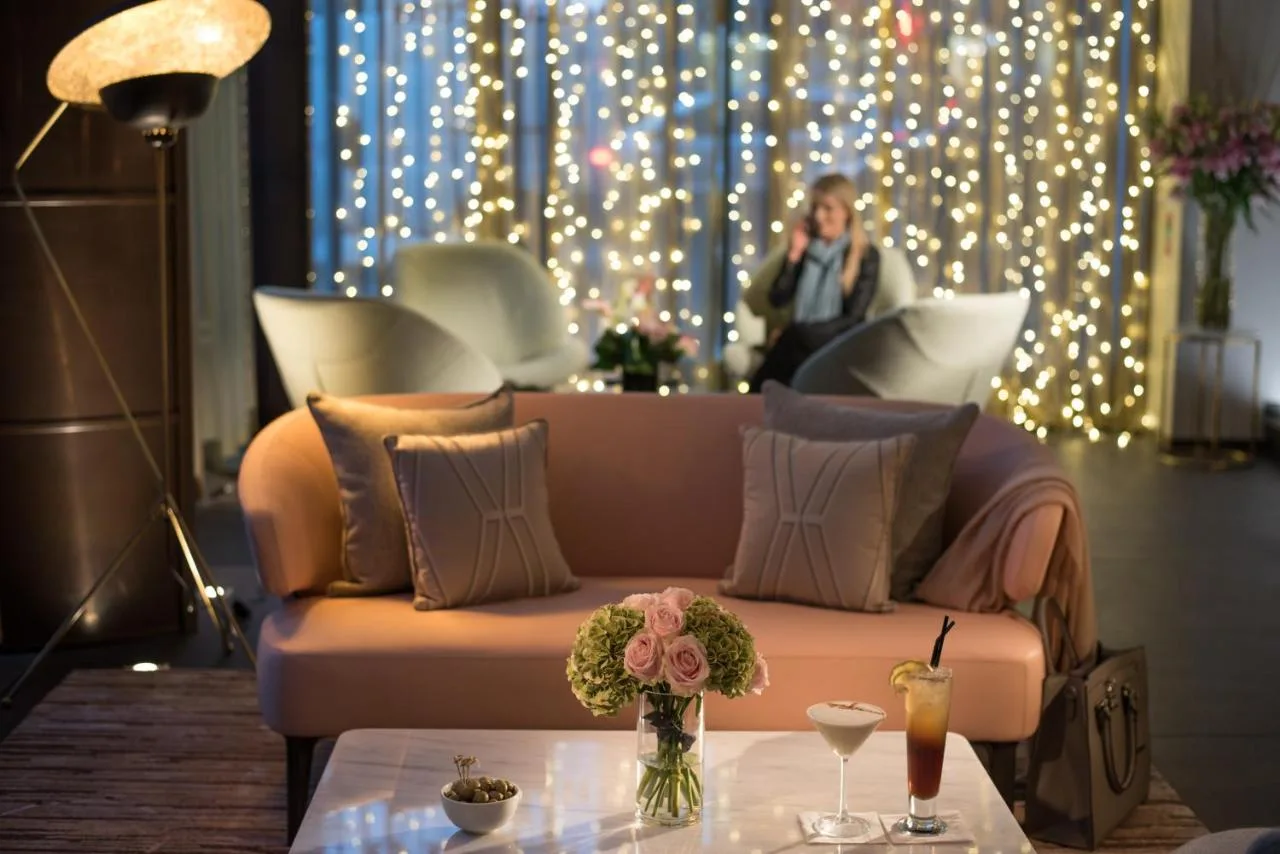 a woman talking on a phone in a room with a couch at The Fitzwilliam Hotel Belfast in Belfast